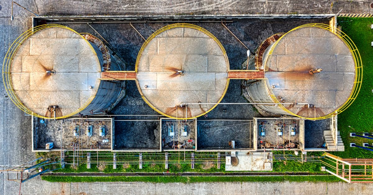 Tre grandi serbatoi industriali per lo stoccaggio di prodotti petroliferi in una raffineria, visti dall'alto